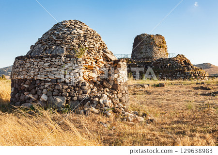 Nuraghe Santu Antine complex with ancient dome-shaped and tower structures in Sardinian countryside at sunset Nuraghe Santu Antine complex with ancient dome-shaped and tower structures in Sardinian countryside at sunset 129638983