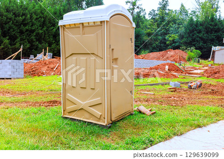 Construction site features portable restroom amidst building activity in residential area 129639099