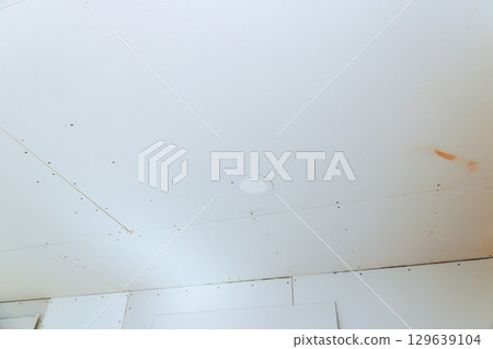 New ceiling board installation in construction project during work day hours 129639104