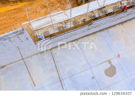 Construction workers building wall on large construction site during works daytime in developing area Construction workers building wall on large construction site during works daytime in developing area 129639107
