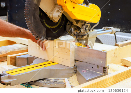 Woodworking with miter saw in workshop during works day hours 129639124