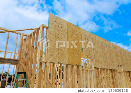 Wooden wall panel being installed during construction of residential building under clear blue sky 129639128