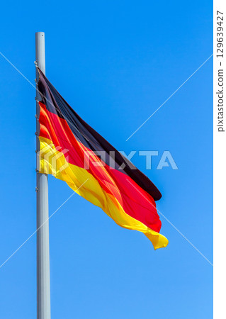 Flag of Germany waving in the wind against the blue sky background. 129639427