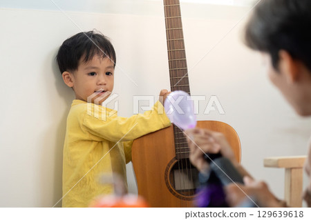 Child with Guitar. Young boy enjoying music and playtime at home. 129639618