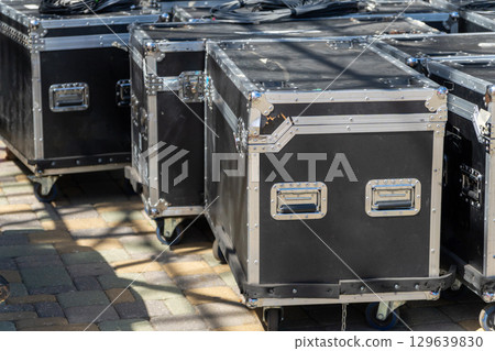 Boxes with sound and lighting equipment and cables near a concert stage during setup. Boxes with sound and lighting equipment and cables near a concert stage during setup. 129639830