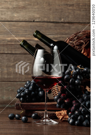 Red wine and blue grapes on an old wooden table. Red wine and blue grapes on an old wooden table. 129640050