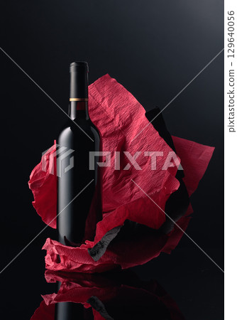 Bottle of red wine on a crumpled paper. 129640056