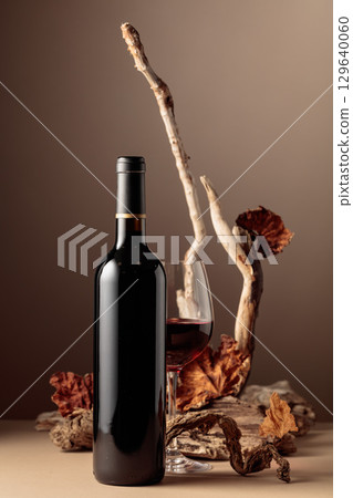 Bottle and glass of red wine with a composition of old wood. 129640060