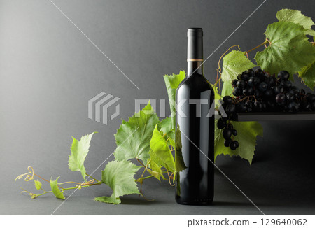 Bottle of red wine with blue grapes and vine branches. Bottle of red wine with blue grapes and vine branches. 129640062