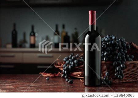 Bottle of red wine with blue grapes. 129640063