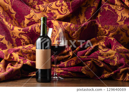Bottle of red wine and retro tapestry with floral ornament. Bottle of red wine and retro tapestry with floral ornament. 129640089