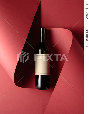 Bottle of red wine with old empty label on a red background. 129640103