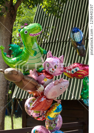 A Colorful Array of Cartoon-Themed Balloons for a Festive Celebration Featuring Dinosaurs, Cats, and Popular Character Designs in a Bright, Cheerful Outdoor Setting A Colorful Array of Cartoon-Themed Balloons for a Festive Celebration Featuring Dinosaurs, Cats, and Popular Character Designs in a Bright, Cheerful Outdoor Setting 129640197