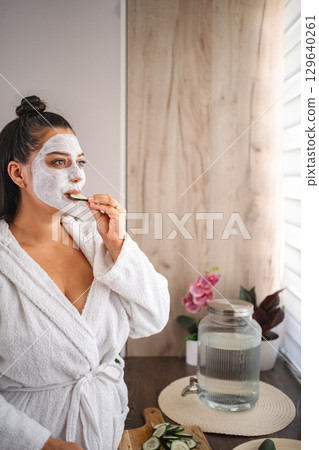 Woman enjoying a beauty treatment with a facial mask and cucumber slices Woman enjoying a beauty treatment with a facial mask and cucumber slices 129640261