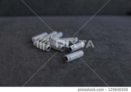 A Collection of Gray Plastic Tubes Spread on a Dark Surface, Ideal for Various Applications, Showcasing Their Unique Design and Textured Surface in a Clean, Minimalist Setting 129640308