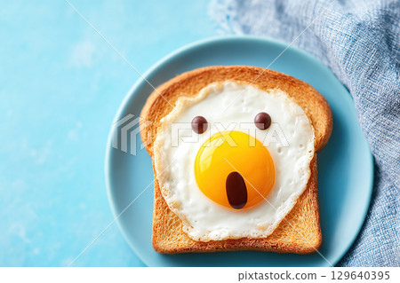 Egg yolk forms shocked face on toast, creating a playful breakfast moment 129640395