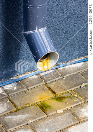 The leaking downspout is causing unsightly stains on the pavement 129640678