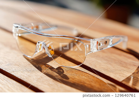 AR glasses resting on a wooden surface in bright daylight highlighting their modern design 129640761