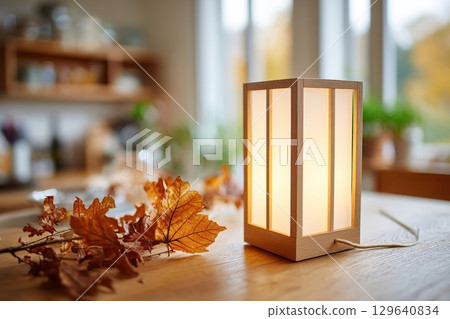 Elegant therapy lamp illuminating a cozy desk adorned with dried autumn leaves 129640834