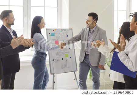 Boss shaking hands female employee, congratulating with achievements or promotion Boss shaking hands female employee, congratulating with achievements or promotion 129640905