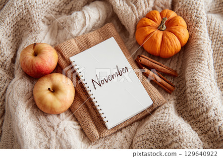 Cozy autumn-themed flat lay featuring a notebook and seasonal produce in November 129640922