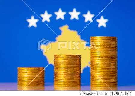 Three coins stacks from lowest to highest on background of flag of Kosovo. Concept of development of economy of Kosovo, financial profit, GDP level 129641064