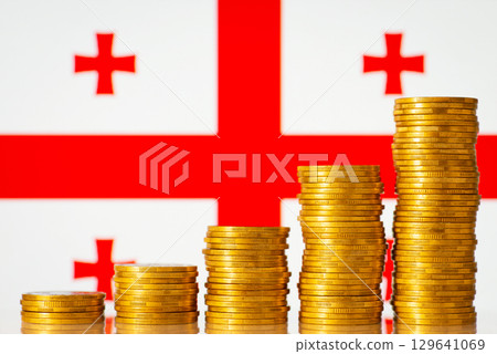 Flag of Georgia with coins stacks from lowest to highest on the foreground. Development of Georgia country concept, financial success, GDP positive level 129641069