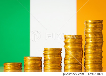 Flag of Ireland with coins stacks from lowest to highest on the foreground. Development of Ireland country concept, financial success, GDP positive level 129641071