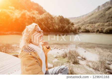 Woman River Mountain Relaxing by a River with Mountain View in the Sunlight Woman River Mountain Relaxing by a River with Mountain View in the Sunlight 129641168