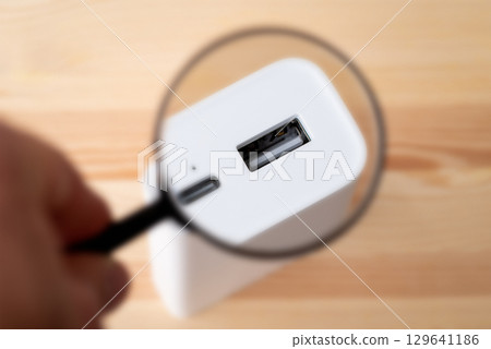 Magnifying glass on USB A port of power bank. Using powerbank for charging concept Magnifying glass on USB A port of power bank. Using powerbank for charging concept 129641186
