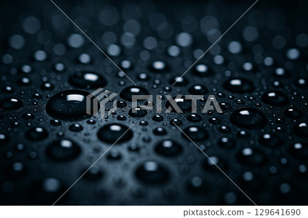 Macro shot of turquoise water droplets with even spacing on a smooth surface in soft lighting 129641690