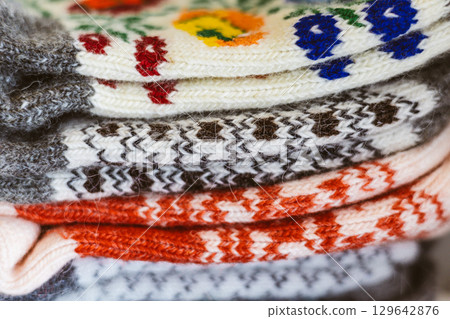 Stacked wool socks with vibrant floral and geometric Ukrainian patterns. A detailed shot of several wool socks displaying vibrant colors A warm visual 129642876
