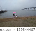 Two girls playing by the lake with an umbrella 129644487