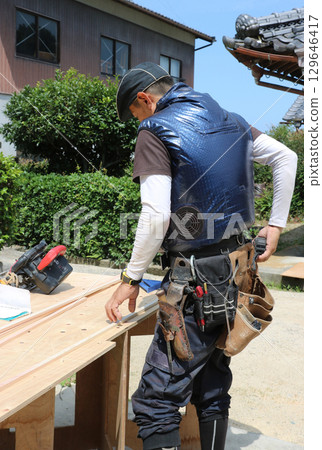 A carpenter is taking out tools from his waist pack with his right hand. A carpenter is taking out tools from his waist pack with his right hand. 129646417