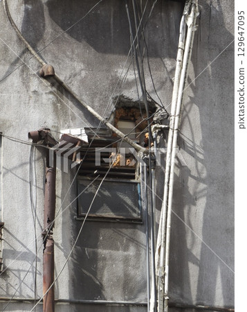 破舊建築的外牆,電線從牆上的洞露出來 破舊建築的外牆,電線從牆上的洞露出來 129647095