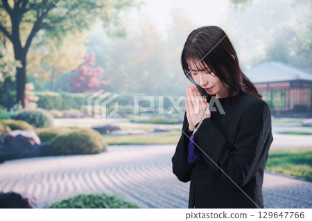 A woman in mourning clothes praying with prayer beads A woman in mourning clothes praying with prayer beads 129647766