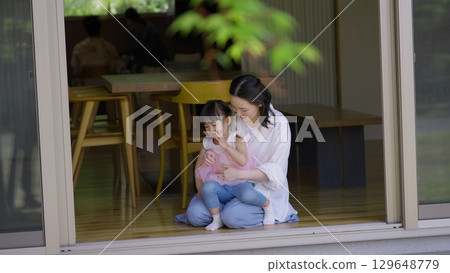 Mother and daughter looking at the garden from the veranda 129648779