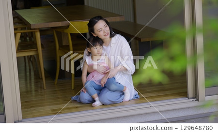 Mother and daughter looking at the garden from the veranda 129648780