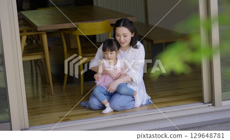 Mother and daughter looking at the garden from the veranda Mother and daughter looking at the garden from the veranda 129648781