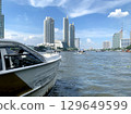 Thailand tourist canal boat on village river and commerical buildings and appartments 129649599