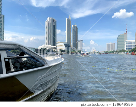 Thailand tourist canal boat on village river and commerical buildings and appartments 129649599