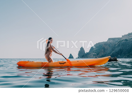 Kayaking Woman Ocean Santorini - A woman paddles a kayak in the ocean near Santorini, Greece. 129650008
