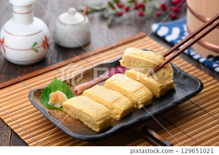 Freshly made, hot rolled omelet in dashi broth. A classic Japanese dish. A perfect table setting for home cooking or izakaya menu. Freshly made, hot rolled omelet in dashi broth. A classic Japanese dish. A perfect table setting for home cooking or izakaya menu. 129651021