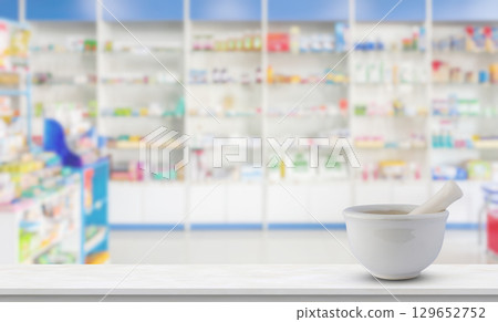 Mortar and pestle on pharmacy counter top with blur medicine shelves in drugstore background Mortar and pestle on pharmacy counter top with blur medicine shelves in drugstore background 129652752