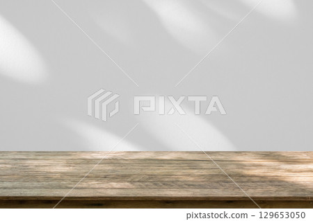 Empty wood table top on white wall texture with tree leaves shadow background Empty wood table top on white wall texture with tree leaves shadow background 129653050