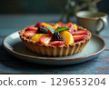 Delicious fruit tart with strawberries, peaches, and blackberries on rustic table 129653204