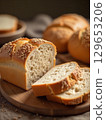 Sliced loaf of sesame bread on wooden board displaying air pockets 129653206
