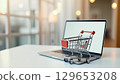 Shopping cart standing on laptop promoting online shopping and e-commerce business 129653208
