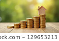 Increasing stacks of coins with a miniature house on top symbolizing savings for a new home 129653213
