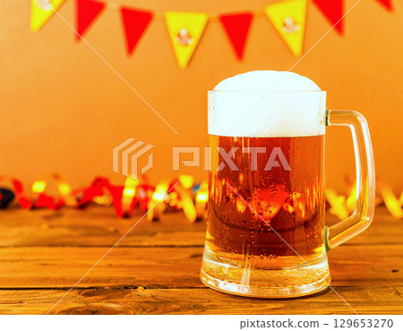 Chilled beer stein glistening with foam, set before Oktoberfest decorations 129653270